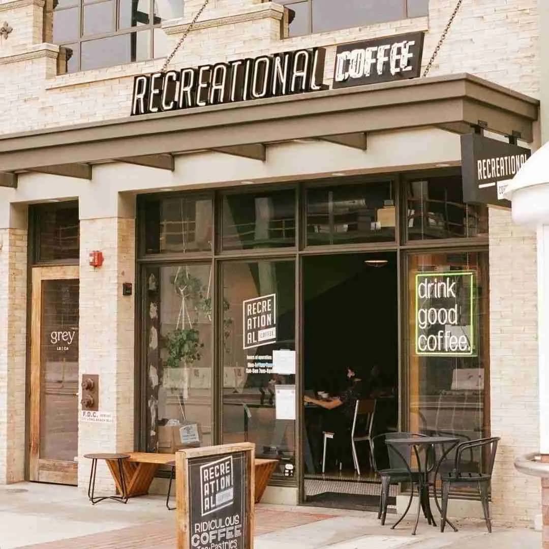 Latte with leaf art beside stacked assorted donuts on dark table against exposed brick wall 2